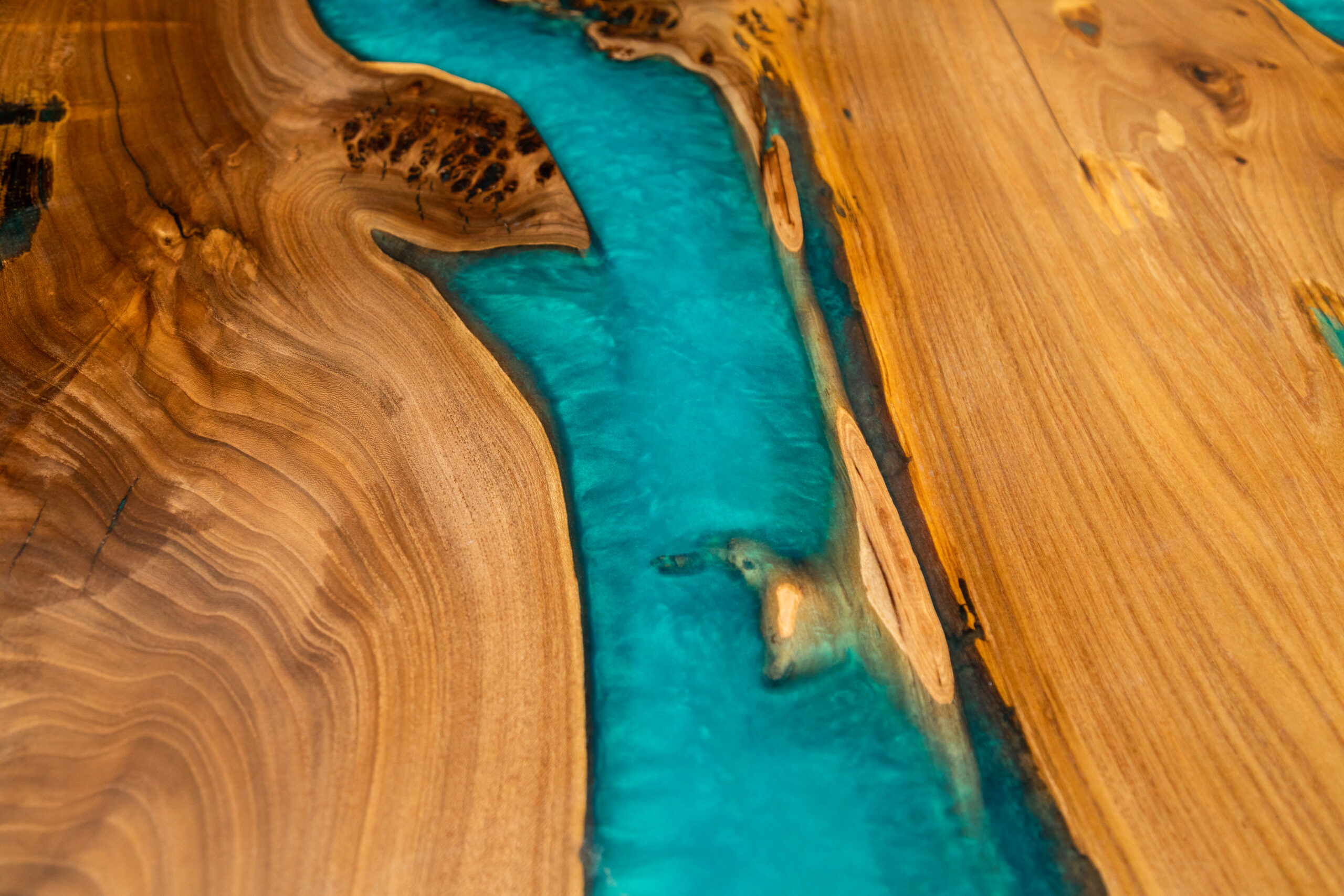Texture of handmade wooden river table with decorative epoxy blue resin